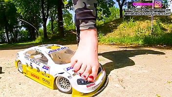 Kati´s bare foot crushing a large DTM racing car bare foot and with her ballerinas